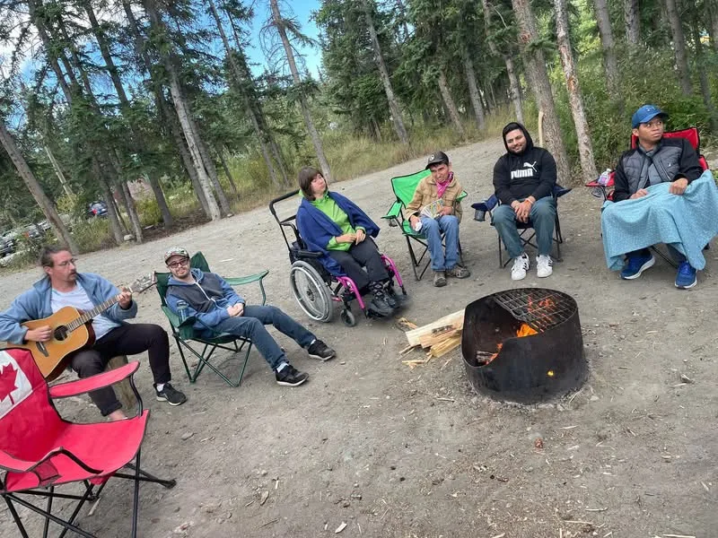 Aaron, Christian, Travis, Elizabeth, and Jagveer gathered around a campfire at Wolf Creek, with Guillaume playing guitar, 2024