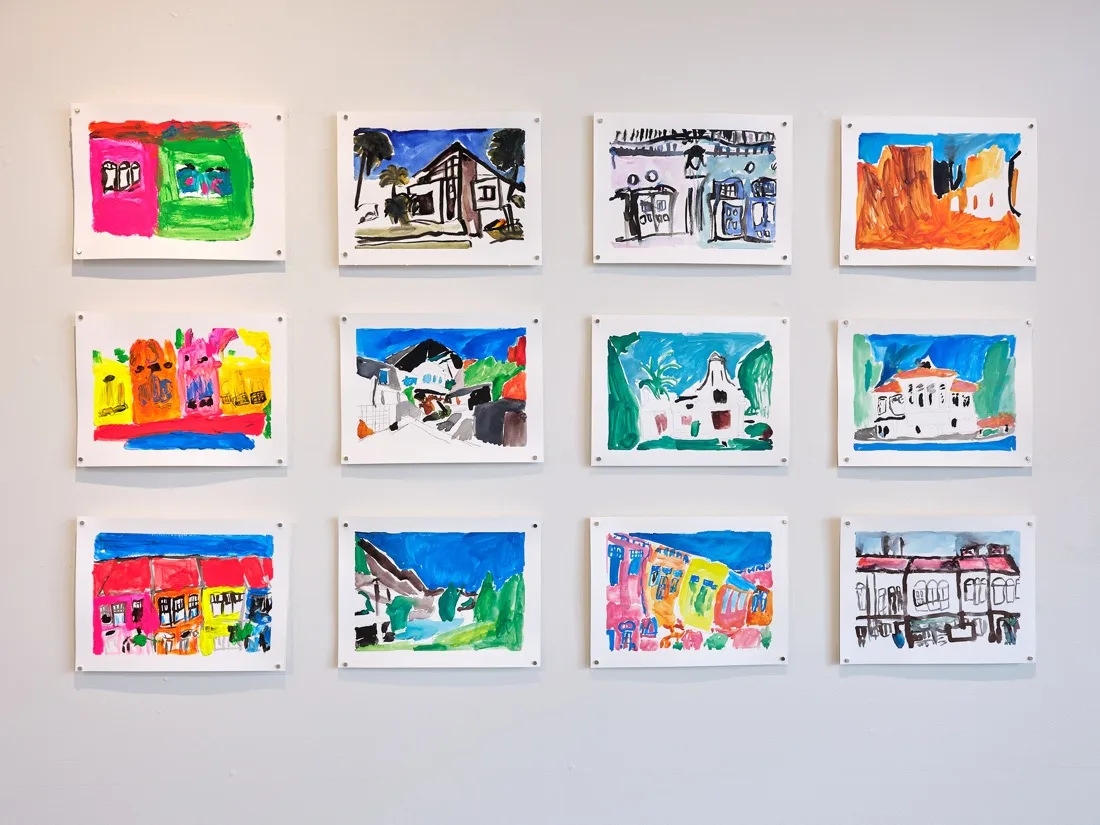A grid of twelve colourful artworks featuring houses, buildings, and neighbourhood scenes