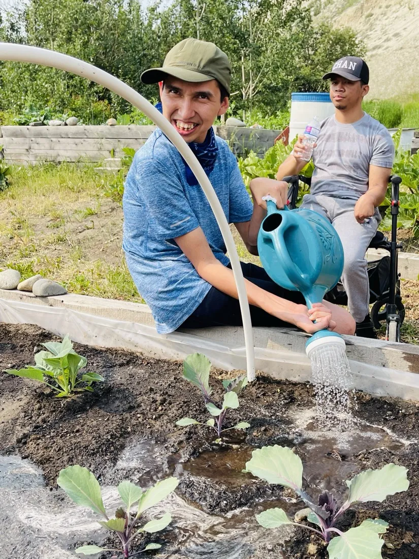 Travis watering plants at the TOZ community garden, 2025