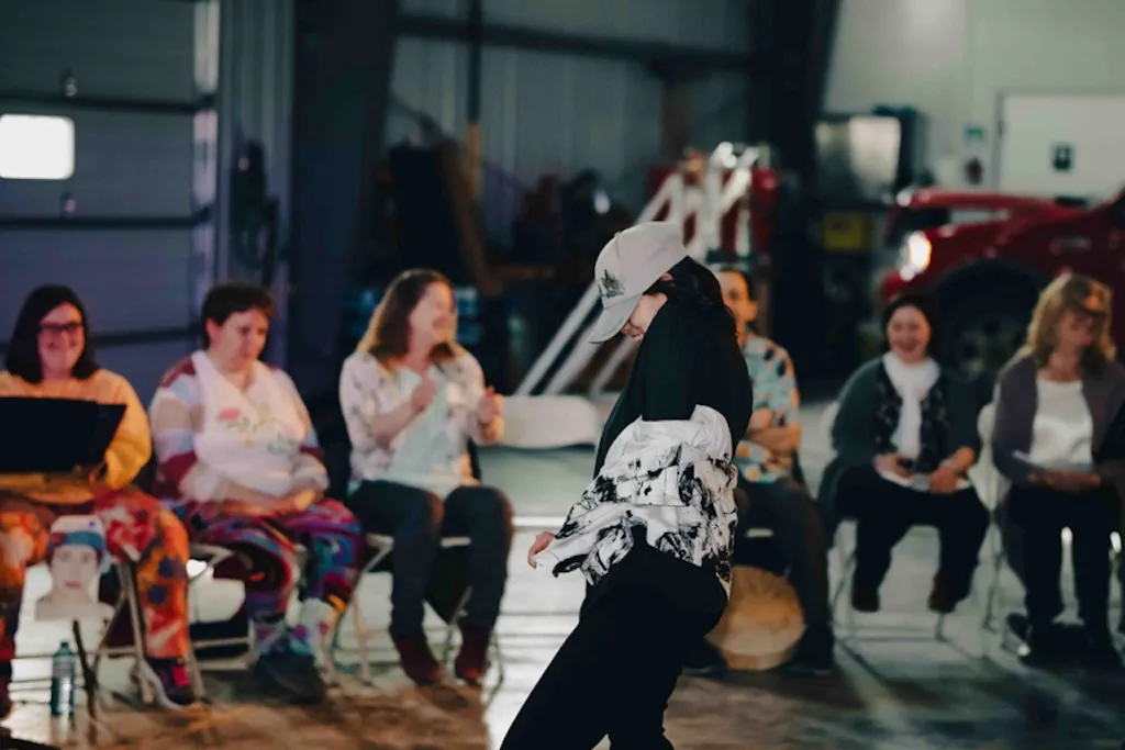 Rachel dancing in front of a seated group during the 2023 Draw Us In event