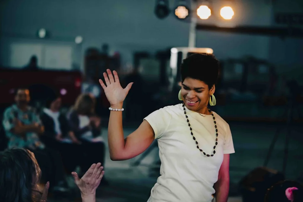 Anna smiling and waving during a group performance, 2023